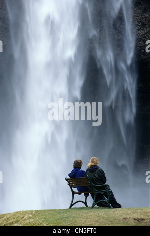 Iceland, Sudurland Region, two women sat on a bench in seljalandsfoss Stock Photo