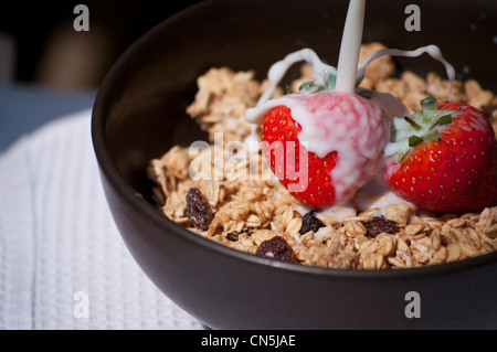 Milk being poured onto strawberries in cereal. Stock Photo