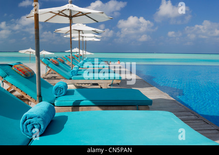 Maldives, South Male Atoll, Dhigu Island, Anantara Resort and Spa Hotel, lounge chairs with umbrellas at the pool near the sea Stock Photo