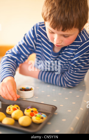 An 8 year old boy making cookies at home in England , Britain , Uk Stock Photo