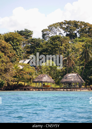 Tropical oceanfront property with thatched palapa and boat house over the sea Stock Photo
