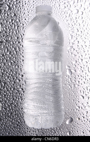 Water bottle laying on its side on a metal surface covered in water drops. Stock Photo