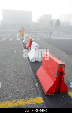 fragment of city in early morning mist fog. concrete road barriers and lower automatic roadblock. Stock Photo