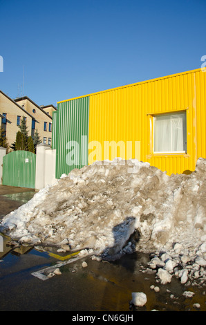 pile of melting snow in spring near industrial building. Stock Photo