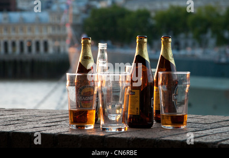 Empty beer bottles and pint beer glasses by River Thames, London. Stock Photo