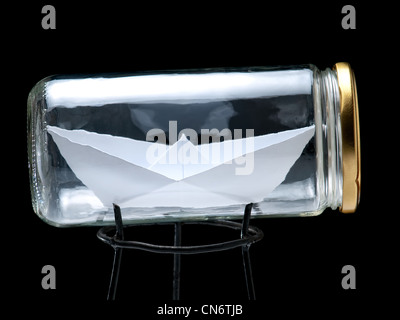 Paper ship in the jar on a black background. Stock Photo