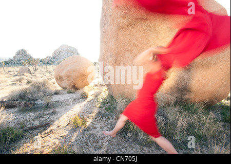 Blurred red woman throwing her red scarf into a stone landscape. Stock Photo