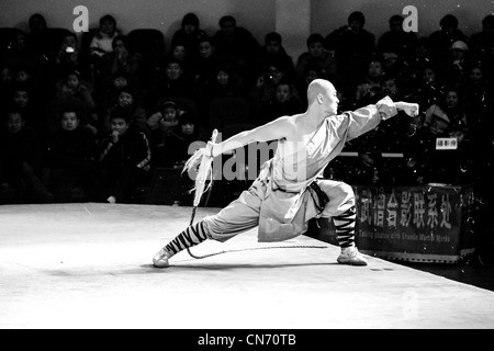 A Shaolin monk with a whip giving a martial arts performance for the audience Stock Photo