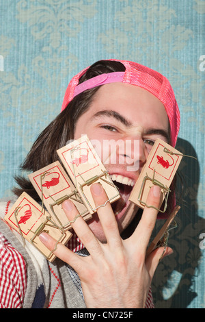 Portrait of caucasian young man screaming with fingers trapped by mouse traps. Stock Photo