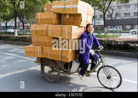 Chinese man on bicycle moving boxes in Shanghai, China Stock Photo
