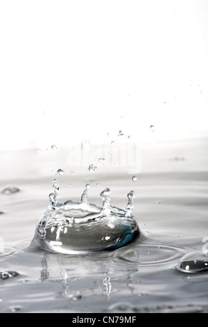 A clear water background texture and splash with droplets forming a crown shape. Shallow depth of field. Stock Photo