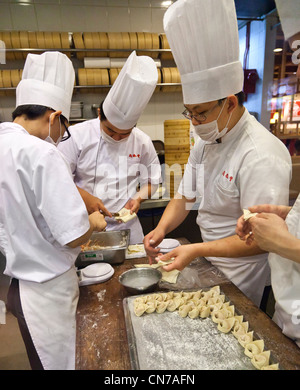 Chinese chefs preparing dumplings in a kitchen, bamboo steamers Stock Photo