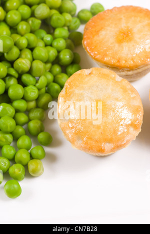 Steak pies served with fresh peas Stock Photo