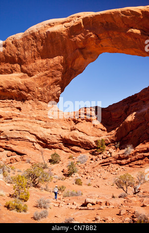 Hiker stands below the massive South Window Arch, Arches National Park, Utah USA Stock Photo
