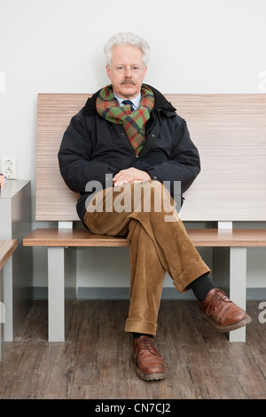 elderly man, sitting patiently in the waiting room of a medical practice, waiting for his turn Stock Photo