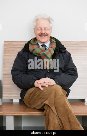 elderly man, sitting patiently in the waiting room of a medical practice, waiting for his turn, smiling Stock Photo