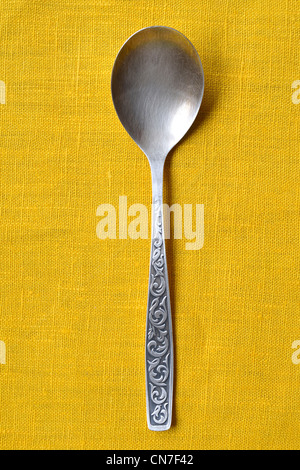 vintage silver spoon on the yellow tablecloth background Stock Photo