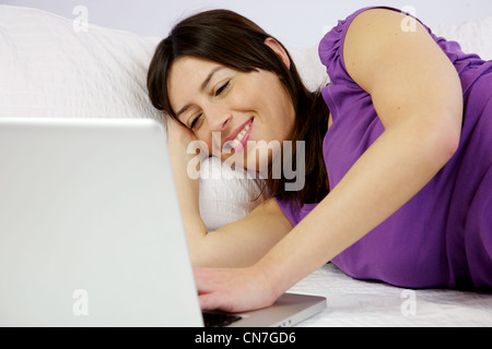 attractive woman reads happy her laptop laying in bed Stock Photo