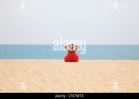 Man relaxing in beanbag on beach Stock Photo