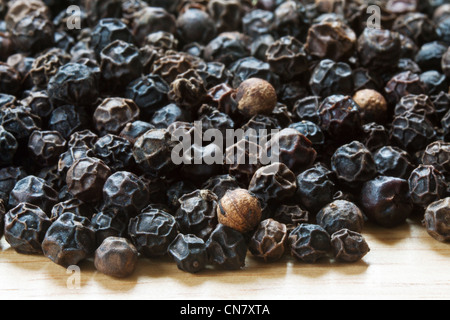 close up of black peppercorns on a wooden table Stock Photo