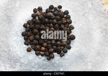 black peppercorns on top of  rock crushed salt