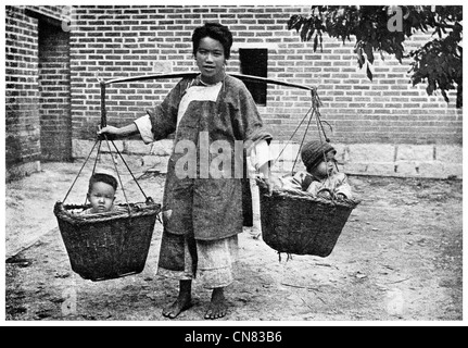 1917 Chinese mother carrying children with a yolk and baskets Stock Photo