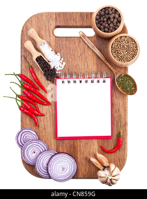 Open notebook and fresh vegetables on an old wooden cutting board. Isolated on white Stock Photo