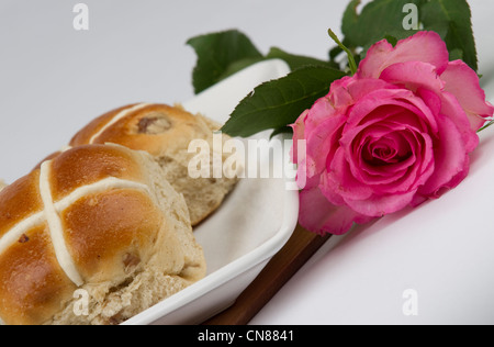 Hot cross buns with pink rose on a white plate Stock Photo