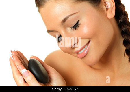 Beautiful young woman massaging her face with hot stone Stock Photo