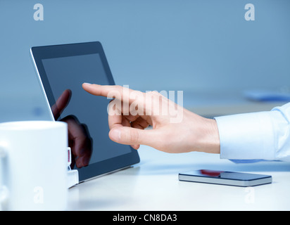 Hand pointing on modern digital tablet pc at the workplace. Stock Photo
