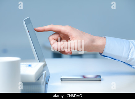 Hand pointing on modern digital tablet pc at the workplace. Stock Photo