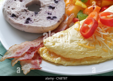 A Sunday brunch cheese omelet served with bacon and a blueberry bagel. Stock Photo