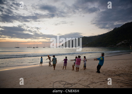 Locals pulling in a fishing net at Nai Harn Beach, Phuket, Thailand