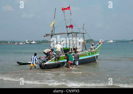 Fishermen preparing to go to sea in their wooden fishing boat Galle Sri Lanka Stock Photo