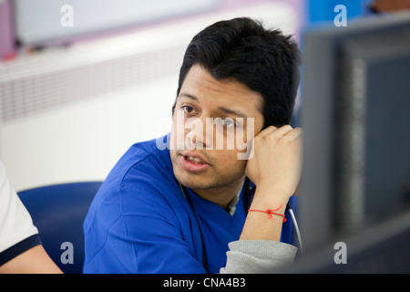 A young male doctor in conference in a busy accident and emergency unit UK Stock Photo