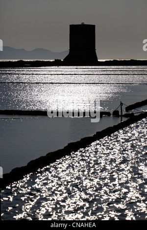 Silhouette of disused windmill at sunset with light relflected in the water in the Salt Pans in Trapani, Sicily, Italy Stock Photo