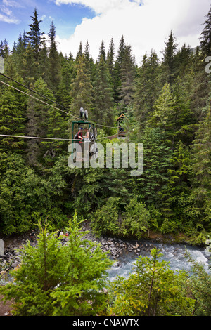 Mountain Bikers riding the hand tram over Winner Creek near Girdwood, Southcentral Alaska, Summer
