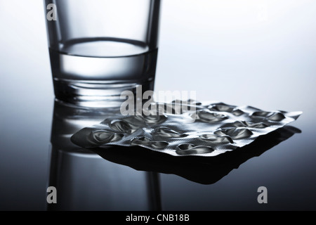Popped blister pack of pills and water Stock Photo