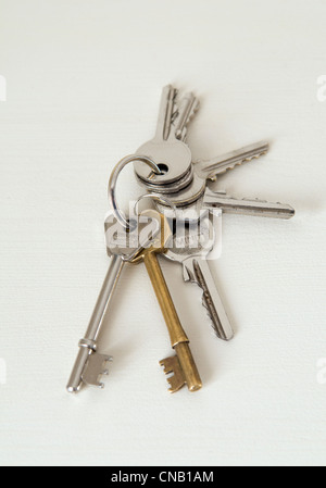 Bunch of various house keys taken against a light coloured wooden table Stock Photo