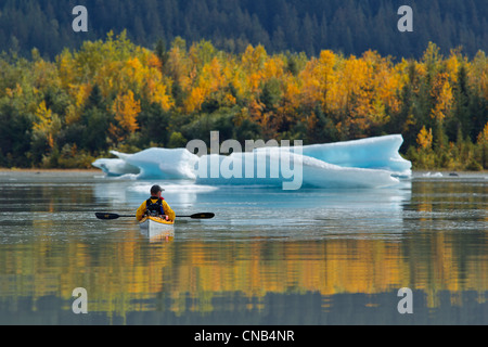 Sea kayaker views an iceberg on the calm water of Mendenhall Lake near Juneau, Southeast Alaska, Autumn Stock Photo