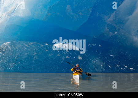 Sea kayaker on Mendenhall Lake with big blue iceberg in the background, Southeast Alaska, Summer Stock Photo