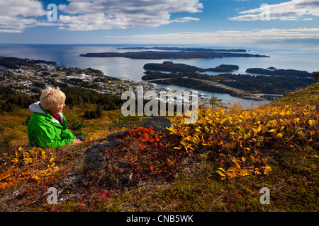 Mature woman relaxes and enjoys view of downtown Kodiak on Pillar Mountain, Kodiak Island, Southwest Alaska, Autumn Stock Photo