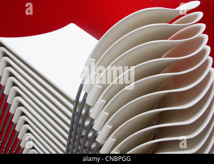 A stack of modern chairs against a red background Stock Photo