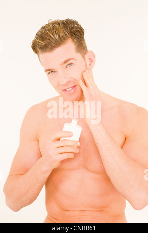 Young man applying aftershave Stock Photo