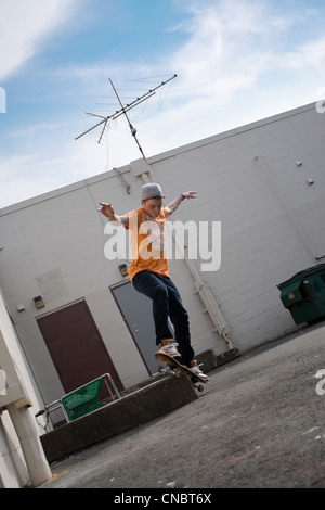 Portrait of a young skateboarder performing a trick in an urban setting. Stock Photo