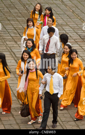Vertical aerial view of young Vietnamese students, the women smartly dressed in bright orange traditonal dress áo dài (ao dai). Stock Photo