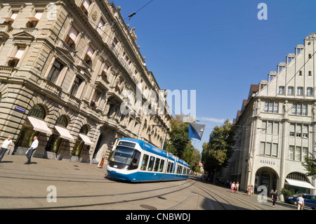 Horizontal wide angle of an electric tram driving down Bahnhofstrasse in central Zurich on a sunny day. Stock Photo
