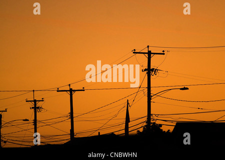 Silhouettes of the power lines and wires in a residential neighborhood backlit by the evening sky. Stock Photo
