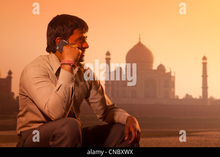 India, Uttar Pradesh, Agra, young man using smartphone with Taj Mahal beyond Stock Photo