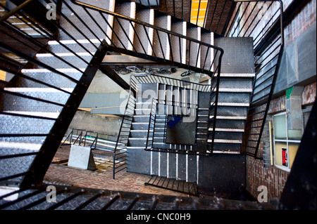 Wide angled photograph of an emergency ire exit staircase made of iron. The stairs are located behind an industrial building in London England. Stock Photo